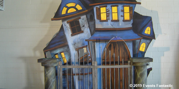 A realistic haunted house display with glowing yellow windows and a gated entrance is shown, eerily reminiscent of a haunted castle. © 2019 Events Fantastic.