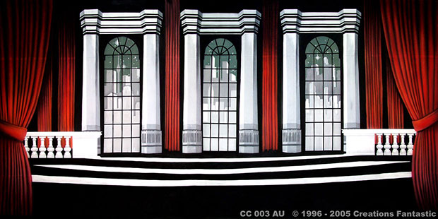 A theater stage set with tall arched windows, framed by red curtains, and a staircase in the center evokes the glamour of a cabaret club. The backdrop features a city skyline, completing the ambiance.