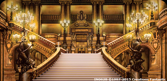 An opulent grand staircase with golden railings, flanked by ornate statues, leads up to a balcony in an elaborately decorated hall with chandeliers and intricate architectural details, reminiscent of the Paris Opera—perfect for a party backdrop.