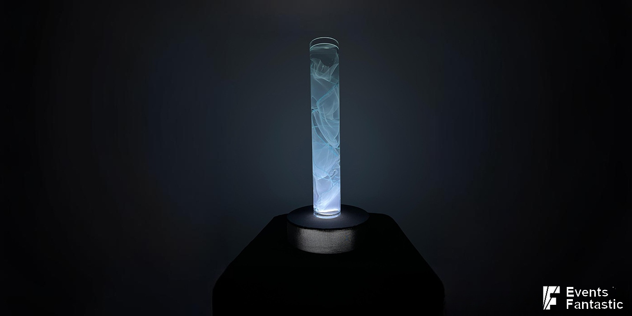 Illuminated cylindrical Flow Centrepiece with abstract patterns on black pedestal against a dark background.