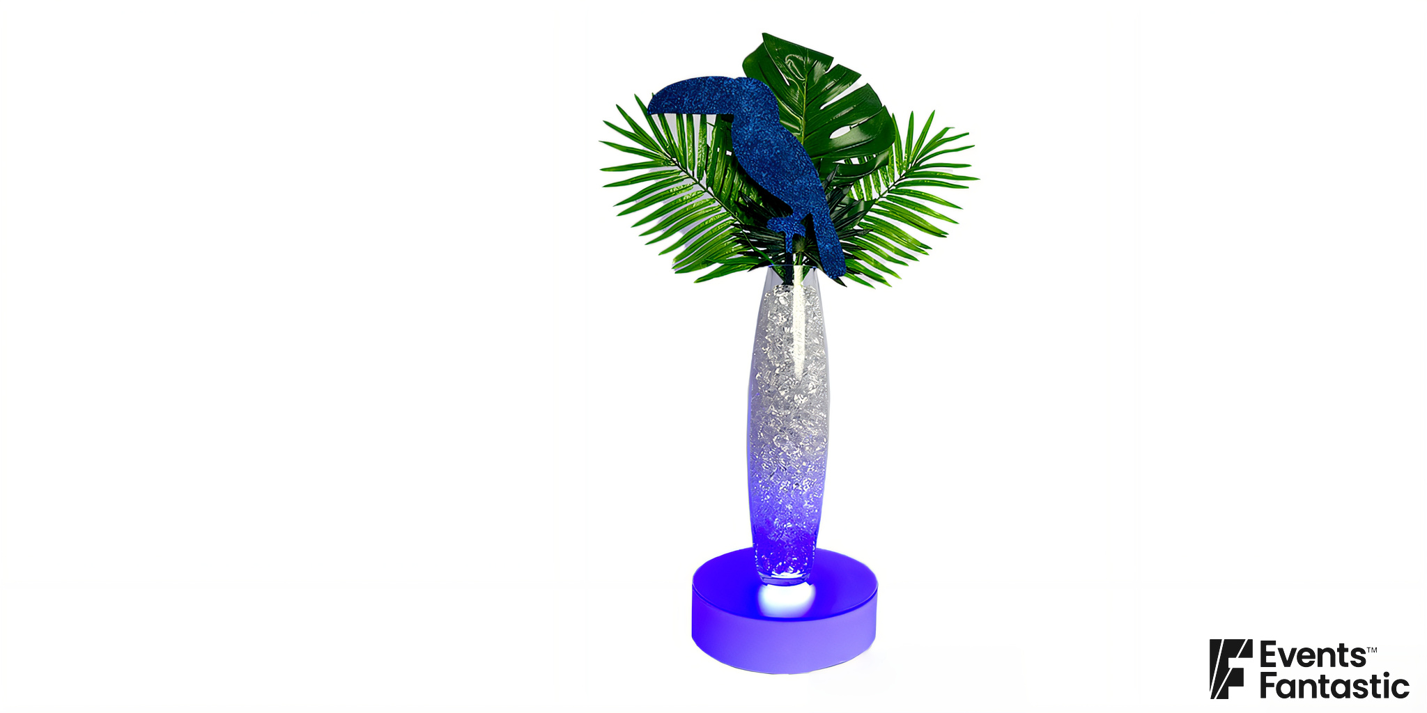 A decorative Havana Nights Toucan Centrepiece featuring a blue toucan perched on green tropical leaves, set in a tall, glittery silver vase with a blue-lit base.