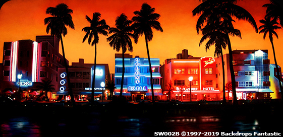 A vibrant cityscape at sunset showcasing neon-lit buildings lined with palm trees, reflecting in the water. Includes brightly colored hotel signs and a backdrop of an orange-red sky.