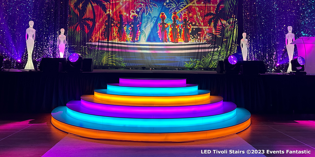 A stage featuring LED-lit white curved Tivoli stairs in front of a vibrant backdrop with silhouetted figures, surrounded by mannequins illuminated by spotlights. Text at the bottom reads: "LED Tivoli Stairs ©2023 Events Fantastic.