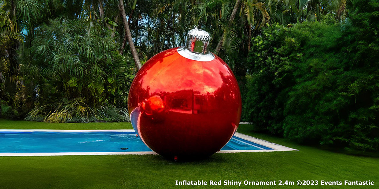 A large 2.4m red shiny ornament is displayed beside a pool in a lush, tropical backyard.