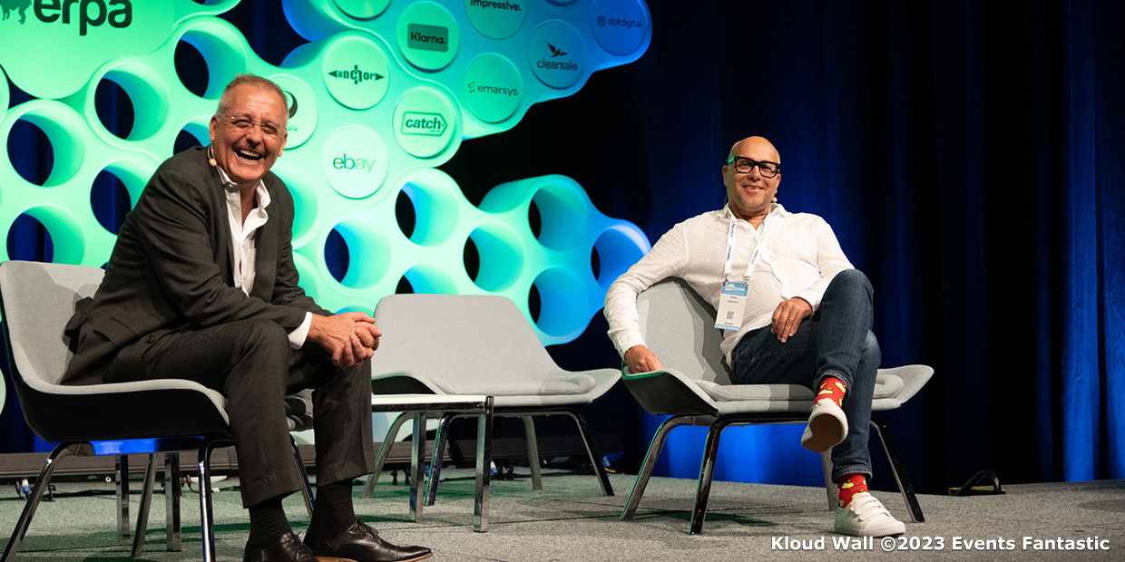 Two men seated on stage with the Kloud Wall backdrop, smiling during a 2023 Events Fantastic event.