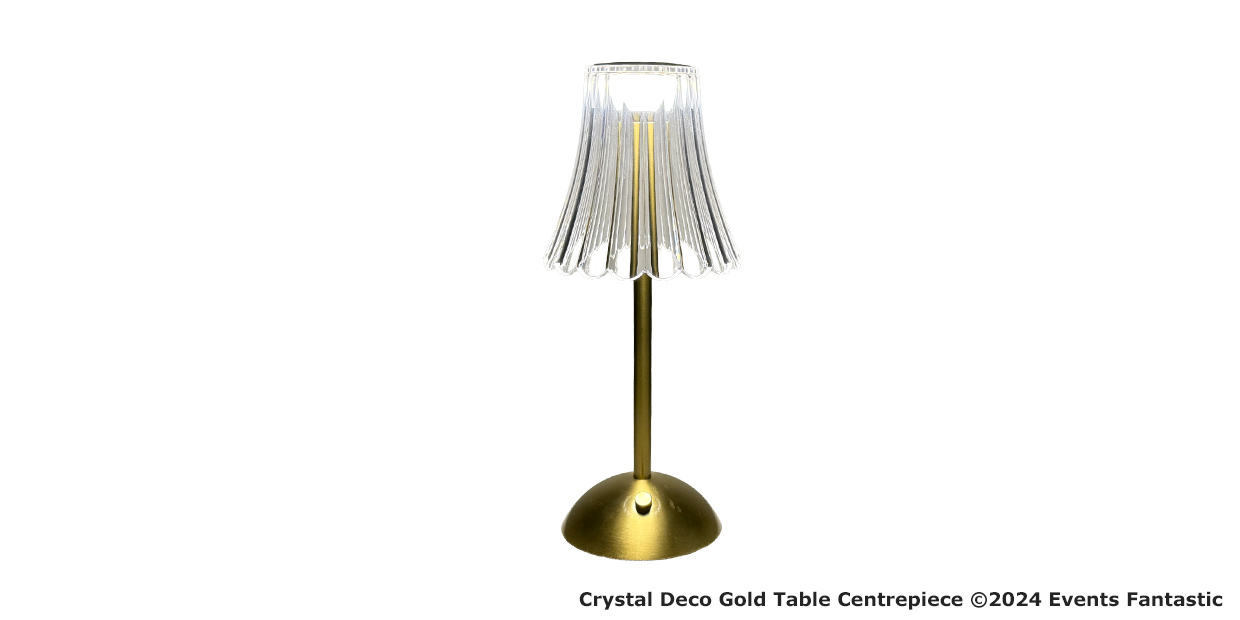 A Crystal Deco gold table lamp with a fluted clear crystal shade stands on a round gold base, illuminated as a stunning Gold LED Centrepiece against a white background.