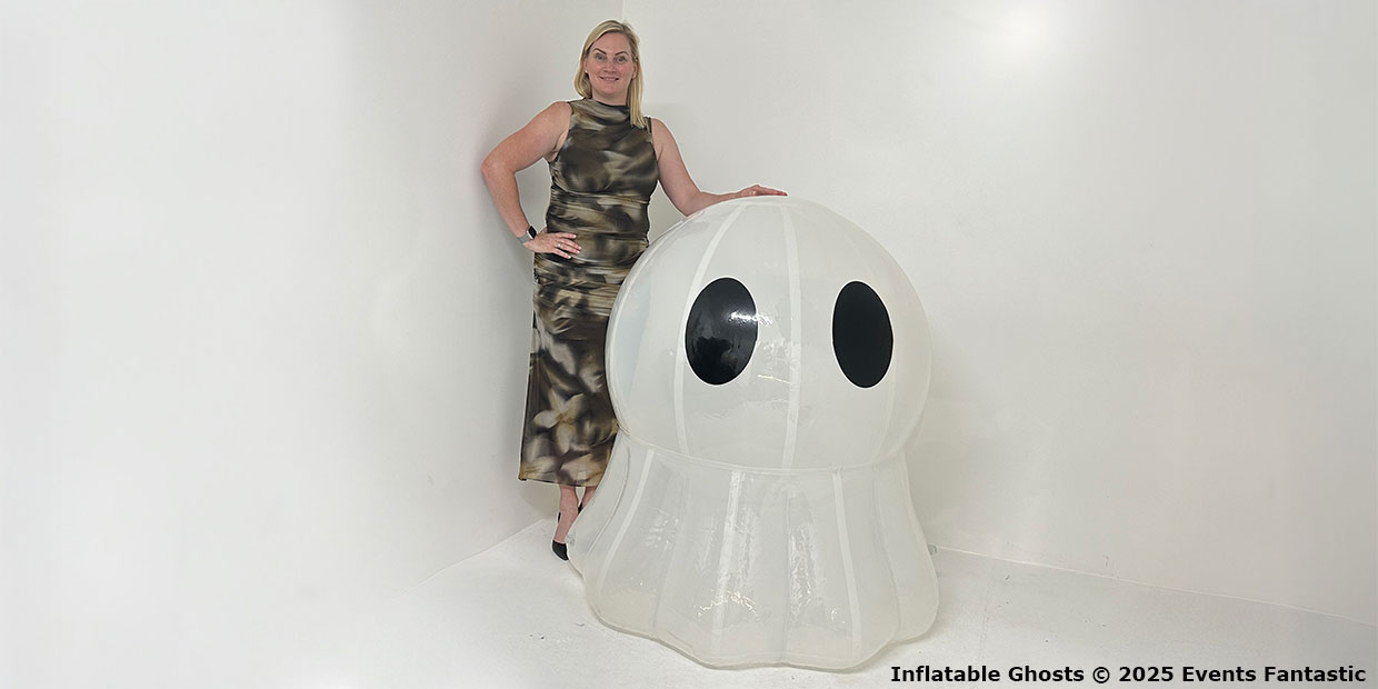 A woman in a patterned dress stands beside a 1.2m tall inflatable ghost with black eyes—a perfect Halloween decoration—in a plain white room.