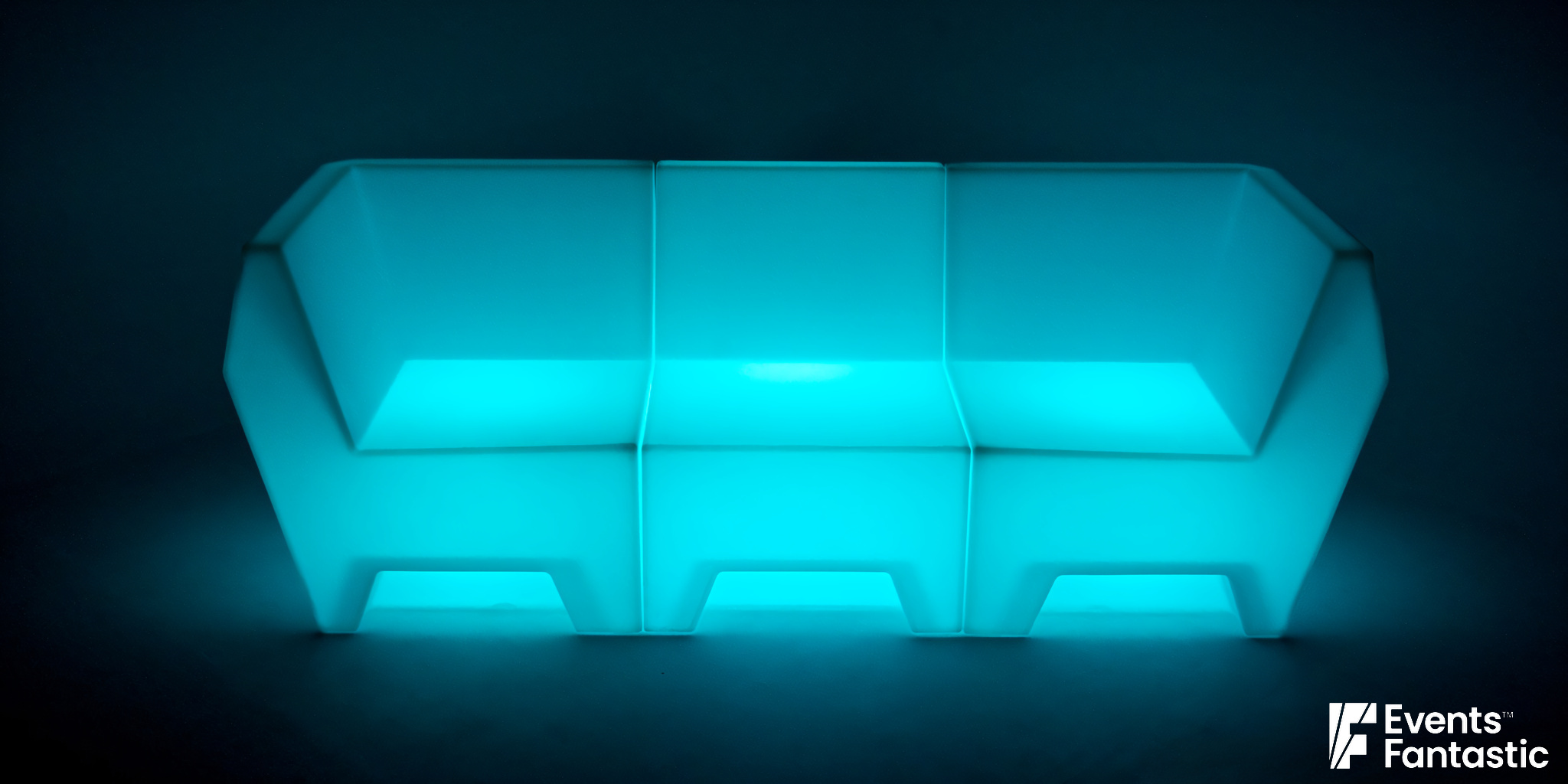 A modern, angular white sofa from our Glow Lounge collection illuminated with blue LED lighting, set against a dark background. "© 2025 Events Fantastic" text appears in the bottom right corner.