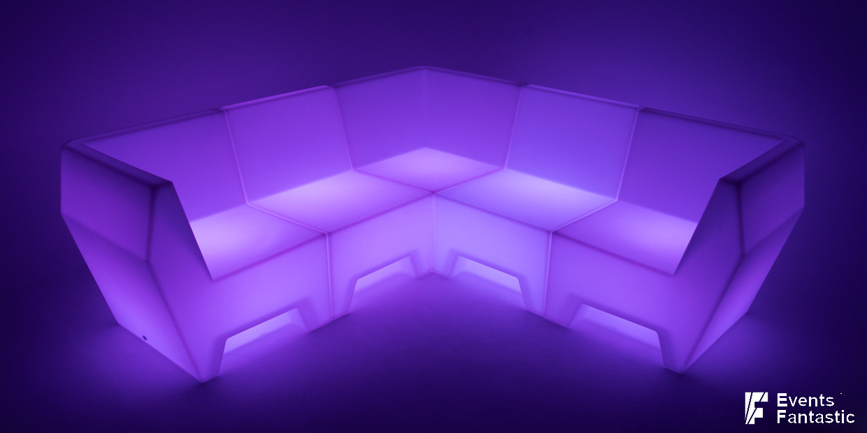 A modular L-shaped sofa with illuminated purple LED lighting, placed in a dimly lit room, creates the perfect Glow V Lounge atmosphere.