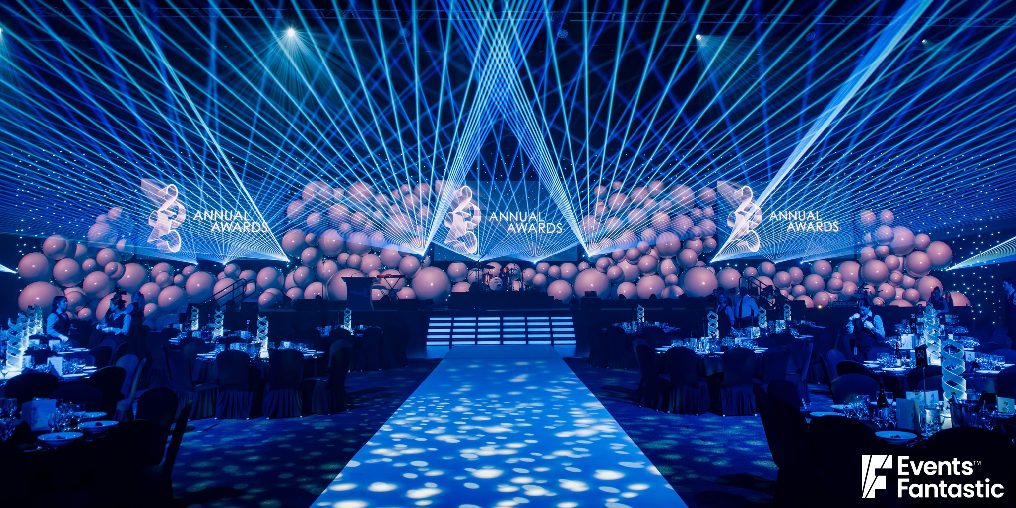 Awards night ballroom with a long wall of inflatable white matt balls across the stage under blue lasers, hire from Events Fantastic.